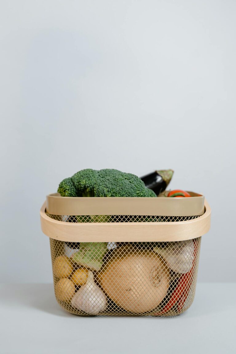 Basket filled with fresh organic vegetables against a light background, ideal for healthy living concepts.